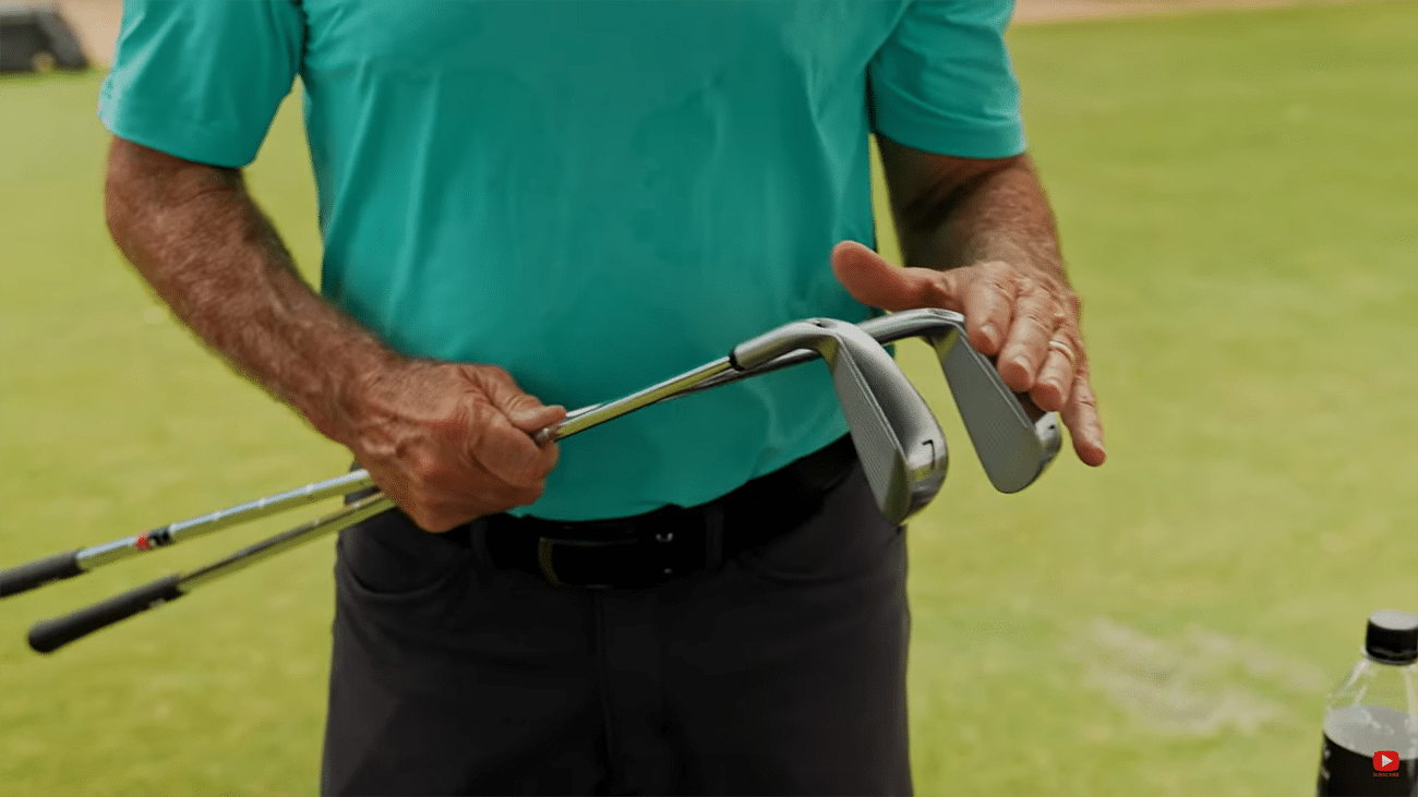 Golfer holding two golf irons on course