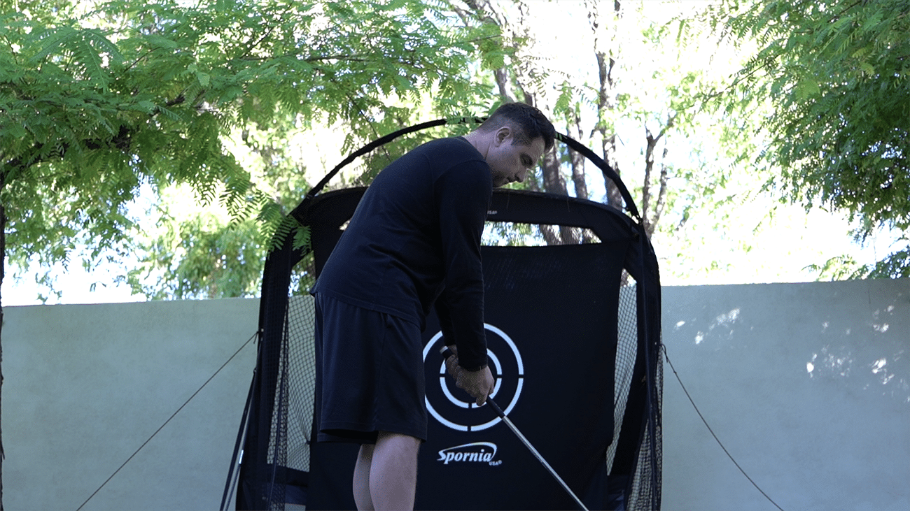 Man practicing golf swing at home net