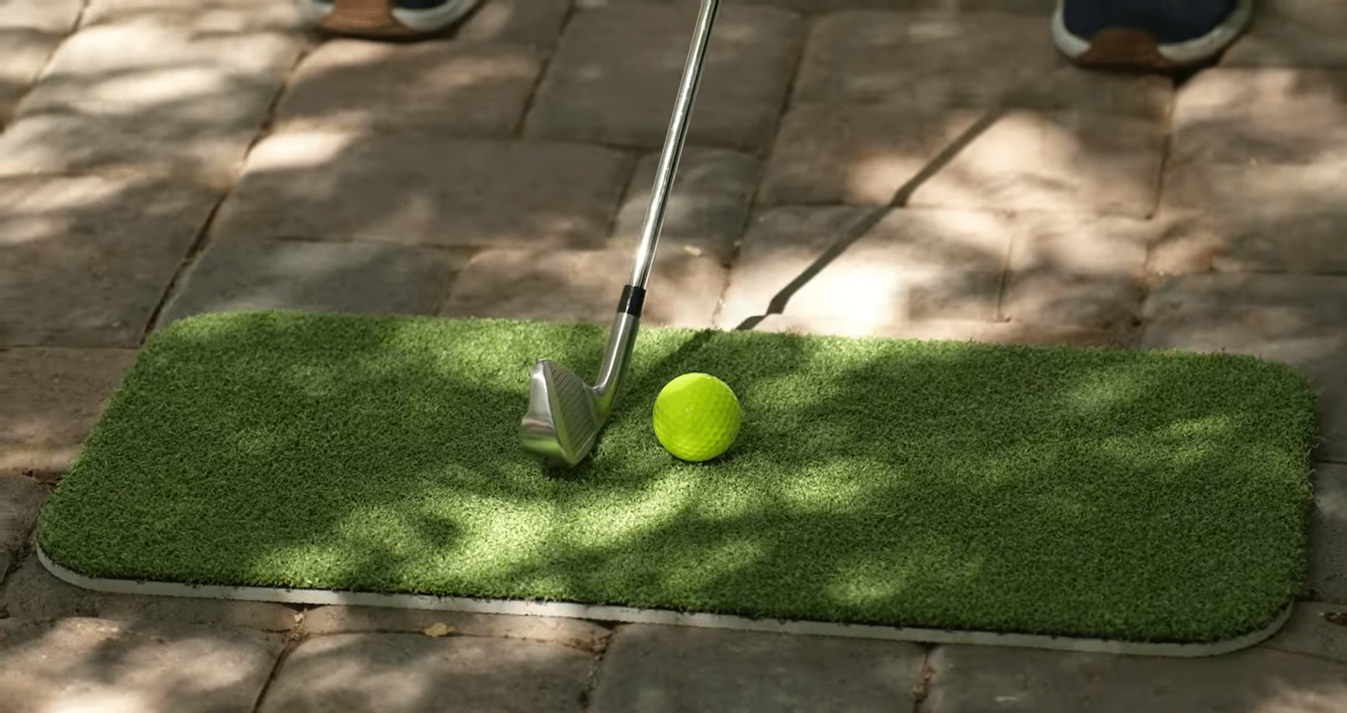 Golf club aiming at yellow ball on mat