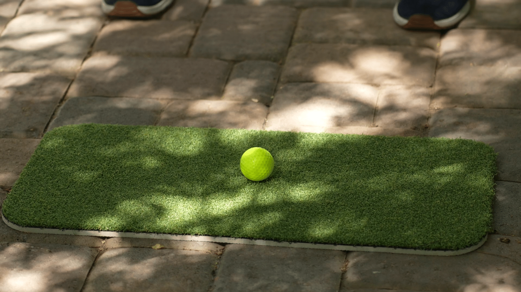 Yellow golf ball on small turf mat