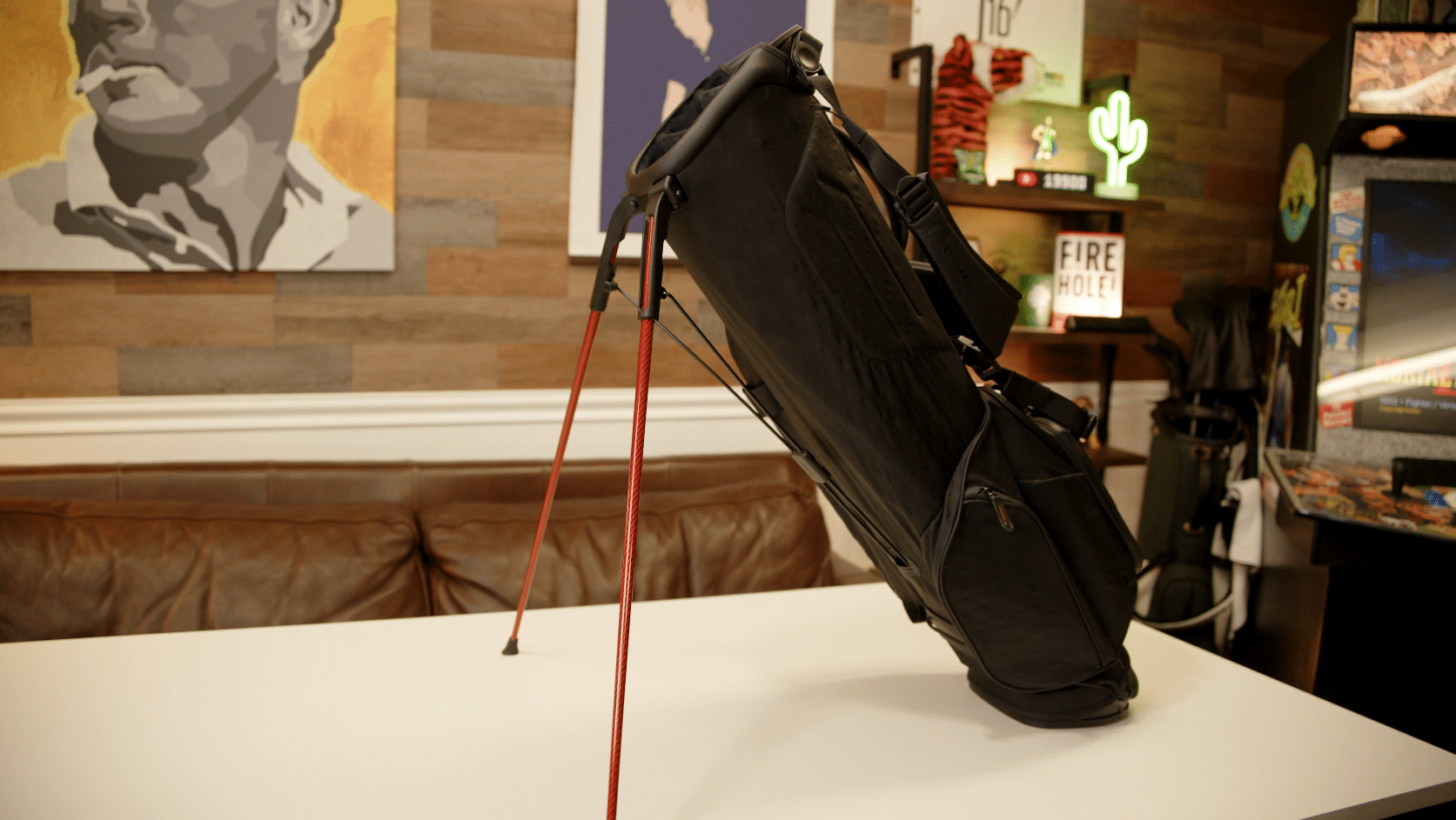Black golf stand bag with red legs on table