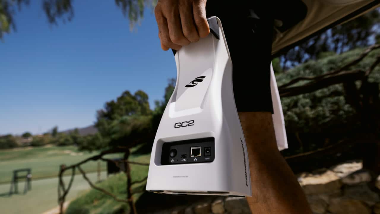 Foresight GC2 launch monitor being carried by its built-in handle on a golf course