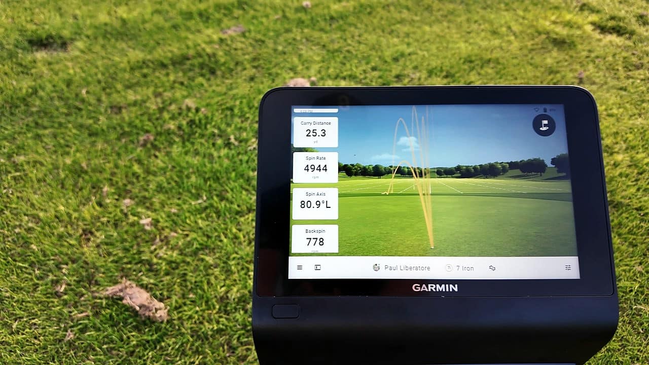Garmin Approach R50 launch monitor sitting on grass outdoors with its screen showing shot data